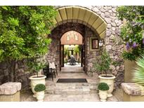 Inviting stone entryway with arched opening and lush landscaping, offering a glimpse of the outdoor dining area at 10040 E Happy Valley Rd # 269, Scottsdale, AZ 85255