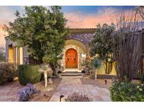 Elegant front entrance with stone archway, a carved wooden door, desert landscaping, and a stone paver walkway at 10040 E Happy Valley Rd # 269, Scottsdale, AZ 85255