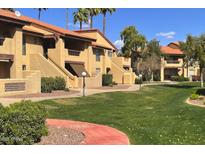 Inviting exterior view of tan townhomes with a red tiled roof, green grass, and mature palm trees at 1351 N Pleasant Dr # 2006, Chandler, AZ 85225