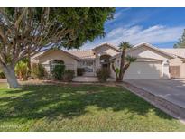 Charming single-story home with a well-manicured lawn, mature trees, and a two-car garage at 1550 E Park Ave, Gilbert, AZ 85234