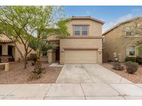 Two story tan home featuring desert landscaping, a two-car garage, and a lovely mature tree at 19072 N Ventana Ln, Maricopa, AZ 85138