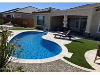 Inviting backyard features a kidney shaped pool, artificial grass, and cozy lounge chairs at 26904 W Kerry Ln, Buckeye, AZ 85396