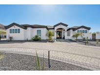 Stunning white home with desert landscaping and a paved circular driveway leading to the grand entrance at 3939 W Fox Rd, Laveen, AZ 85339
