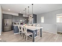 Open kitchen and dining area featuring an eat-in island, stainless steel appliances, and gray cabinetry at 14870 W Encanto Blvd # 2084, Goodyear, AZ 85395