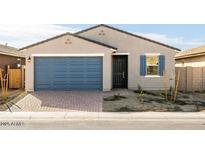 Charming single-story home with a blue garage door, stone accents, and desert landscaping at 8613 W Warner St, Tolleson, AZ 85353