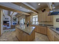 Open kitchen featuring an island with granite countertops, wooden beams, stainless appliances, and light wood cabinetry at 8619 E Silver Saddle Dr, Carefree, AZ 85377