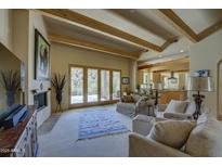 Spacious living room with wooden beams, a fireplace, comfortable seating, and patio access, perfect for relaxation and entertaining at 8619 E Silver Saddle Dr, Carefree, AZ 85377