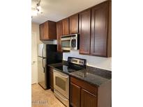 Traditional kitchen with stainless steel microwave, range, dark cabinets, and black countertops at 14145 N 92Nd St # 2004, Scottsdale, AZ 85260