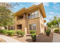 Inviting exterior showcases a two-story condo with a balcony, manicured bushes, and a landscaped yard at 20100 N 78Th Pl # 1013, Scottsdale, AZ 85255