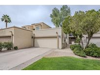 Beige two-story house with a two car garage, green grass and desert landscaping at 8100 E Camelback Rd # 143, Scottsdale, AZ 85251