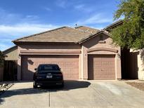 Home exterior showcases a three-car garage and desert landscaping in the front yard at 13542 W Port Au Prince Ln, Surprise, AZ 85379