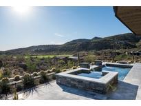 Luxury pool and spa with a waterfall feature, overlooking a lush desert landscape and mountain views at 41248 N 96Th St, Scottsdale, AZ 85262