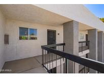 Exterior view of the condo building featuring second-floor entrance and balcony with dark metal railings at 7494 E Earll Dr # 308, Scottsdale, AZ 85251