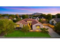 Stunning single-story home boasts a terracotta roof and a well-manicured lawn with mature trees against a mountain backdrop at 17755 E Colt Dr, Queen Creek, AZ 85142