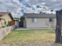 View of backyard with grassy area, block wall, and neutral colored exterior at 421 E Desert Dr, Phoenix, AZ 85042