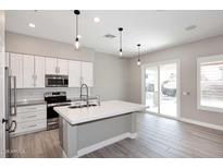 Modern kitchen features white cabinets, an island, and stainless steel appliances at 7741 E Journey Ln, Scottsdale, AZ 85255