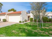 Charming single-story home features a terra cotta roof, attached garage and lush green lawn at 9734 W Kerry Ln, Peoria, AZ 85382