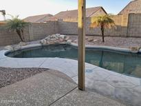 Backyard pool with rock waterfall feature and decorative concrete, surrounded by privacy wall and desert landscaping at 1006 W 15Th Ln, Apache Junction, AZ 85120