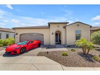 Charming single-story home with a well-manicured front yard and a striking red sports car in the driveway at 187 E Santa Lucia Ln, Queen Creek, AZ 85140