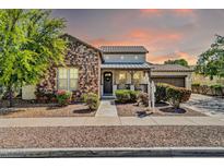 Charming single-Gathering home with stone accents, a cozy porch, and manicured landscaping at sunset at 4013 N Founder Cir, Buckeye, AZ 85396