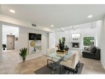 Bright living room featuring fireplace, clerestory windows, and a glass dining table near comfortable seating at 7245 E Buena Terra Way, Scottsdale, AZ 85250