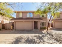 Charming two-story home featuring a two-car garage, arched windows, and mature trees for shade at 7650 E Williams Dr # 1011, Scottsdale, AZ 85255