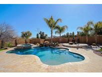 Inviting backyard pool featuring a spa, waterfall feature, and mature tropical landscaping for a resort-like feel at 13627 E Monument Dr, Scottsdale, AZ 85262