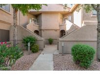 Condo building exterior featuring stucco walls, landscaped walkways, and stairs leading to upper-level units at 15050 N Thompson Peak Pkwy # 1035, Scottsdale, AZ 85260