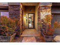 Inviting home entrance with brick accents, beautiful plants, and a security screen door at 29794 N Little Leaf Dr, San Tan Valley, AZ 85143