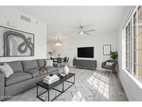 Bright living room with modern gray sofa, neutral decor, ceiling fan, and an open dining area at 510 N Alma School N Rd # 158, Mesa, AZ 85201