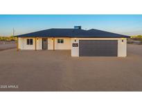 Charming single-story home featuring a gray garage door, minimalist landscaping, and stylish exterior lighting at 16567 N Slate Ln, Maricopa, AZ 85139