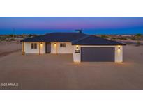 Beautiful single-story home showcasing modern exterior lighting, gray garage door, and minimalist desert landscaping at 16567 N Slate Ln, Maricopa, AZ 85139