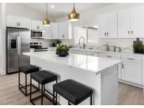 Modern kitchen with white cabinets, stainless steel appliances, and a quartz countertop island with seating at 16567 N Slate Ln, Maricopa, AZ 85139