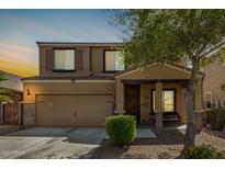 Two-story home features a large front yard, desert landscaping, attached two-car garage, and covered porch at 38085 W San Capistrano Ave, Maricopa, AZ 85138