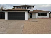 Charming two-story home featuring a dark garage door, manicured landscaping, and a cozy front porch at 5431 W Cholla St, Glendale, AZ 85304
