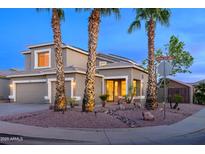 Charming two-story home featuring a well-manicured desert front yard with three palm trees and a neutral toned stucco at 15123 W Custer Ln, Surprise, AZ 85379