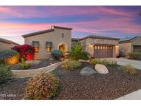 Beautiful home with a lush landscaped yard featuring cacti, colorful flowers, and a stone-accented garage at 27280 N Makena Pl, Peoria, AZ 85383