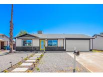 Charming single-story home features a yellow front door, a two-car garage, and low maintenance desert landscaping at 3437 E Acoma Dr, Phoenix, AZ 85032