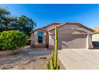 Charming single-story home with a two-car garage, desert landscaping, and a sunny blue sky at 42568 W Bunker Dr, Maricopa, AZ 85138
