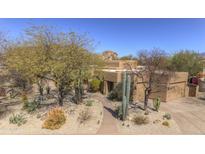 Attractive tan home featuring desert landscaping, walkway, mature trees, and a two-car garage at 7322 E High Point Dr, Scottsdale, AZ 85266