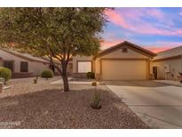 Charming single-story home featuring a two-car garage, desert landscaping, and a mature shade tree at sunset at 1285 E Cottonwood Rd, San Tan Valley, AZ 85140