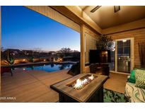 Inviting covered patio with a fire pit and views of the sparkling pool and desert landscape at 1705 W Stephanie Ln, San Tan Valley, AZ 85144