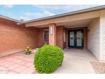 Charming brick home featuring a secure metal screen door and lush, well-manicured landscaping at 5022 E Magic Stone Dr, Phoenix, AZ 85044