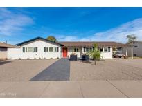Charming single-story home featuring a red front door and a well-manicured gravel yard with a sleek, dark gray walkway at 5110 E Verde Ln, Phoenix, AZ 85018