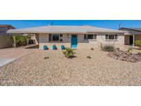 Charming home exterior with low maintenance desert landscaping, a carport, and a turquoise front door at 7526 E Mckinley St, Scottsdale, AZ 85257