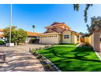 Charming two-story home with a red tile roof, a spacious driveway, and artificial grass at 8807 E Dahlia Dr, Scottsdale, AZ 85260