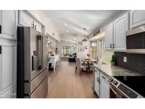 Bright, open kitchen with white cabinets, stainless steel appliances, and views of the dining and living areas at 8807 E Dahlia Dr, Scottsdale, AZ 85260