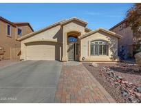 Single-story home featuring a two-car garage, desert landscaping, and a brick walkway to the front door at 2414 W White Feather Ln, Phoenix, AZ 85085