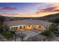 Expansive, modern home featuring large garage doors, a tile roof, and a circular driveway against a sunset backdrop at 6602 N Arizona Biltmore Cir, Phoenix, AZ 85016