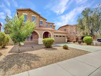 Charming two-story home featuring a tile roof, arched entryway, and a well-maintained, low-water front yard at 15093 W Glenrosa Ave, Goodyear, AZ 85395